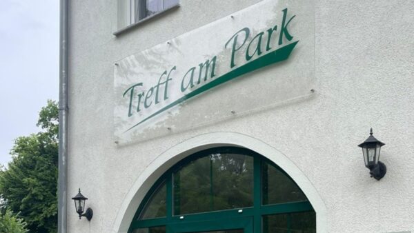 Alt Text für Bilder sagte: Gebäude mit Schild „Treff am Park“